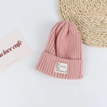 Detail of pink knitted beanie featuring a ribbed texture and white woven label patch - Head Circumference 50-58cm / Pink