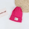 Close-up of hot pink ribbed knit beanie with white lettered woven label on a clean background - Head Circumference 50-58cm / Rose Red
