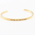 Golden stainless steel cuff bracelet engraved with Nursing is a work of heart - nursing is a work of heart