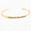 Polished gold cuff bracelet featuring engraved Believe In Your Dreams mantra - BELIEVE IN YOUR DREAMS