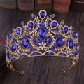 Macro shot of gold baroque crown with blue teardrop gemstones on a dark wood surface - KC Gold With Blue Rhinestone
