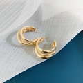 Detailansicht der goldfarbenen C-förmigen Creolen auf blau-weißem Stoffhintergrund - Mehrlagige C-Form Creolen (3) / Gold
