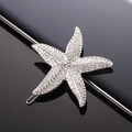 Silver metal starfish hair clip with white sparkling rhinestones on a black reflective surface - Metallic Silver Starfish