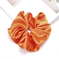 Detailed view of glossy orange satin scrunchie with silky texture for hair styling - Orange
