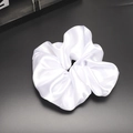 Detail showing the glossy texture and folds of a white satin silk scrunchie on dark background - White