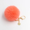 Detail van koraalkleurige pluche pompon sleutelhanger met gouden sneeuwvlok en haak - 8cm Diameter / Oranjerood