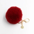 Detail eines roten flauschigen Bommel-Schlüsselanhängers mit goldenem Schneeflocken-Anhänger - Burgunderrot