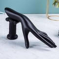 Detail of matte black hand-shaped jewelry display stand on a classical ionic pillar base - Black
