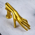 Golden hand-shaped jewelry stand on a Roman pillar base for ring and necklace display - Gold