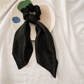 Close-up of black satin scrunchie with long ribbons on a decorative ceramic plate - Black