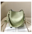 Vue détaillée d'un sac seau en cuir vert pâle posé sur un fauteuil beige élégant - Vert