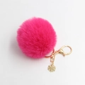 Detail van rozerode pluizige bont pompon sleutelhanger met goudkleurige sneeuwvlok hanger - 8cm Diameter / Rozerood