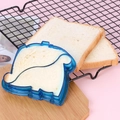 Blue plastic sandwich cutter mold sealing a puppy-shaped toast on a wooden board - Dinosaur Blue