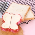 Primer plano de un cortador de sándwich rosa de mariposa cortando pan en tabla - Mariposa-Rosa