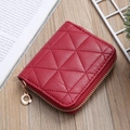 Detalle de mini cartera de cuero acolchado rojo con cremallera dorada sobre madera - Burdeos