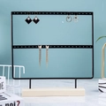 Two-tier black metal earring display stand with solid wooden base on blue background - 44 Holes / Black