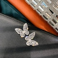 Primer plano detallado de pendientes de mariposa con circonitas sobre fondo de texturas - Mariposa de Circonita con Pin de Plata