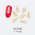 Detailed view of fleur-de-lis gold nail charms with rhinestones on a red manicure - Gold Fleur-de-lis White Rhinestone Style (3730)