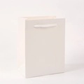 Detail of white paper shopping bag with white rope handles on a clean white background - White
