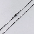 Detalle de una cadena de bolas negra con cierre de langosta sobre fondo gris - Negro / 45cm