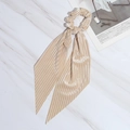 Elegant champagne pleated silk hair scrunchie with long ribbon on marble surface - Beige