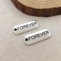 Silver rectangular metal tag with Forever engraving on a beige fabric background - Forever
