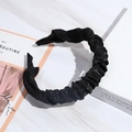 Detail of a black knotted headband made of pleated fabric on a marble surface - Black