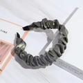 Detail of grey pleated fabric headband with metallic sheen on marble background - Gray
