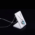 Blue teardrop crystal necklace displayed on white triangular stand against black background - Small / White