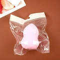Pink teardrop makeup sponge in clear bag packaging on a red-brown surface - Gourd Shape (Individual Bag) / Pink