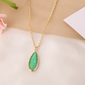 Detalle de collar de cadena dorada con un colgante de gema verde en forma de gota - Rectángulo Verde