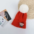 Detailaufnahme einer roten Weihnachts-Strickmütze mit weißem Bommel und kleiner Rentierpuppe - Orange (Weihnachtselch)