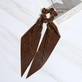 Brown pleated velvet scrunchie with long ribbons on a white marble background - Coffee