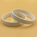 Two premium white silicone wristbands displayed on a vibrant orange background - White