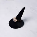 Golden crown ring with white rhinestones on black velvet stand over marble background - Single Finger Round Base