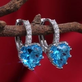 Makroaufnahme der herzförmigen blauen Zirkon-Ohrringe mit weißen Steinen auf elegantem Ast - Aqua