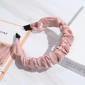 Detail shot of a pink satin pleated headband on a white marble surface with soft lighting - Pink