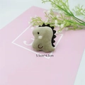 Dettaglio di spilla in peluche a dinosauro kaki su carta rosa, misura 5,5x4,5 cm - Dinosauro verde (Toppa fai-da-te)