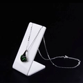 Detail of silver drop necklace with green gemstone on professional display stand - Medium / White