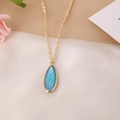 Detalle de collar dorado con colgante ovalado de piedra azul sobre tela de fondo beige - Rectángulo Azul