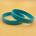 Custom teal silicone wristbands stacked on a warm yellow background in a minimalist style - Sky Blue