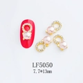 Detalle de joyería para uñas con perla rosa y marco dorado con cristales en una uña - Estilo 5050 Perla Rosa Claro Diamante