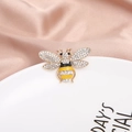Golden bee brooch with yellow enamel and sparkling crystals on a white ceramic plate - Enamel Bee