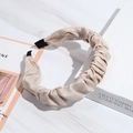 Macro detail of beige pleated fabric headband with subtle shimmer on marble surface - Beige/Champagne