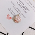 Detailed view of baroque irregular pinkish pearl pendant with gold plated edge on a card - Pink