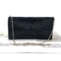 Dettaglio borsa clutch in rete metallica nera con catena d'argento su rivista - Nero