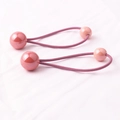 Gros plan d'élastiques à cheveux roses à billes pour filles sur tissu rose doux - Rose foncé