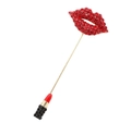 Dettaglio di una spilla a nappa dorata con labbra in cristallo rosso e un rossetto mini - Labbra Rosse Rossetto