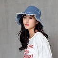 Blue denim bucket hat with distressed frayed edges on a female model against a grey wall - M / Blue
