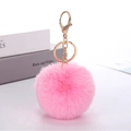 Detailed view of a soft pink faux rabbit fur pom pom keychain with a gold metal clasp - Pink